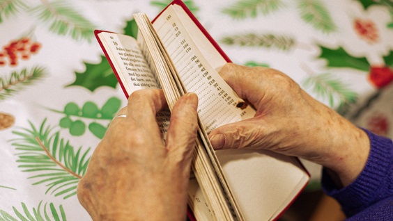 Med sangbogen i hånden og et smil på læben! Beboeren er ivrig efter at finde den næste melodi – og glæder sig allerede til næste torsdag, når pigerne igen besøger Lundbyescentret.